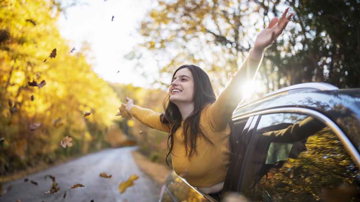 Lady with arms up in the leaves