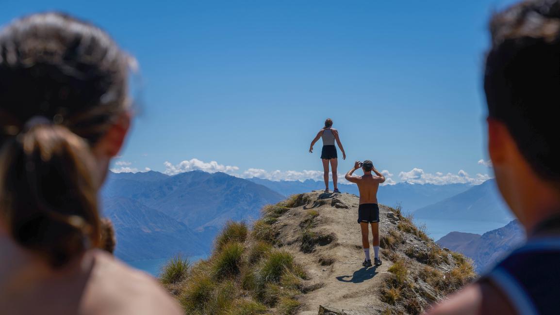 Women and man looking at 2 people on mountain